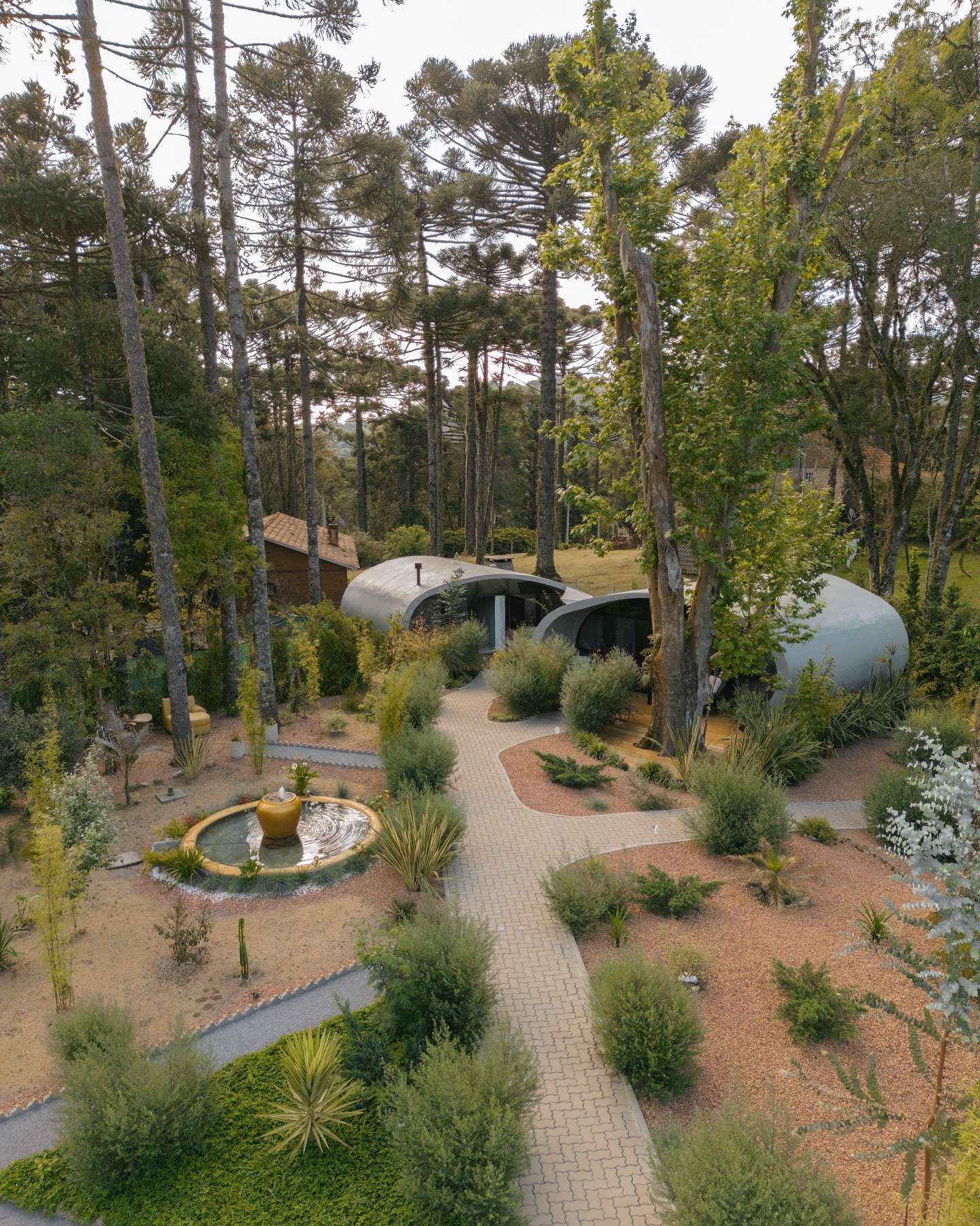 Jardim com caminhos, fonte e cabanas entre as árvores